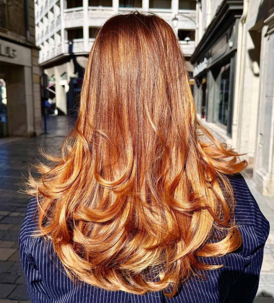 Reflets chaleureux sur cheveux longs ondulés, réalisation du salon Céline D